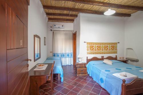 a bedroom with two beds and a table in it at I Mandorli in Lotzorai