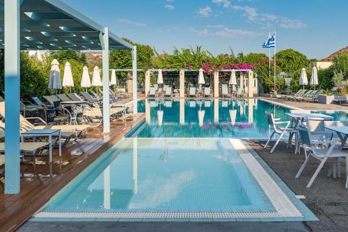 a swimming pool with chairs and tables and umbrellas at Nissia Kamares in Kardamaina