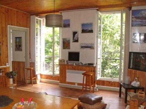 d'un salon avec une télévision et de grandes fenêtres. dans l'établissement Beau Soleil, à Eaux-Bonnes