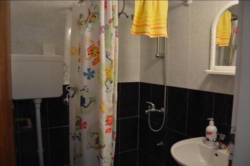 a bathroom with a shower curtain and a sink at Guest House Vera in Ulcinj