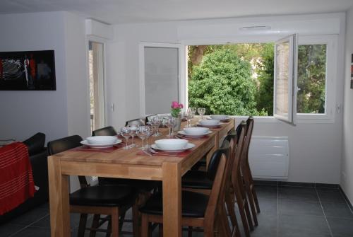 une table de salle à manger avec des chaises et une grande fenêtre dans l'établissement Le Prado de Sète, à Sète