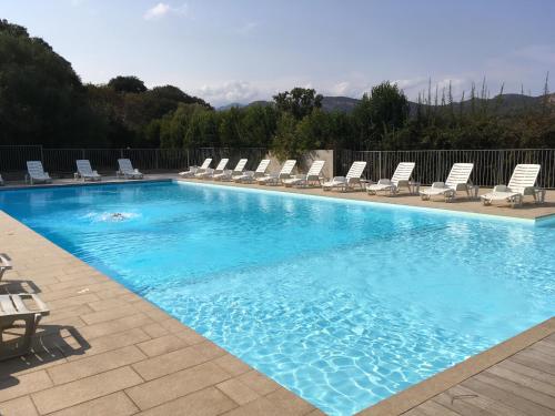 a large swimming pool with chairs and a group at Lavu Santu in Sainte-Lucie de Porto-Vecchio