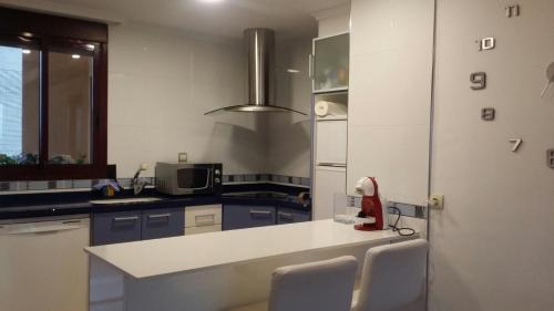 une cuisine avec un comptoir blanc et un appareil rouge dans l'établissement Apartamento con Vista al Mar, à Tavernes de Valldigna