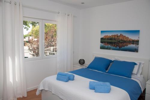 a bedroom with a bed with blue pillows and a window at Pine Tree Villa in Cascais