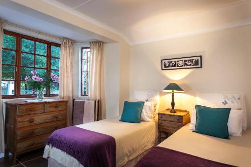 una camera da letto con due letti, un comò e una finestra di Antique Silk Self Catering Unit a Grahamstown