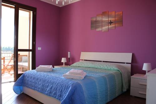 a bedroom with purple walls and a bed with towels on it at Villetta Airone in Birgi Vecchi