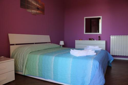 a bedroom with purple walls and a bed with towels on it at Villetta Airone in Birgi Vecchi