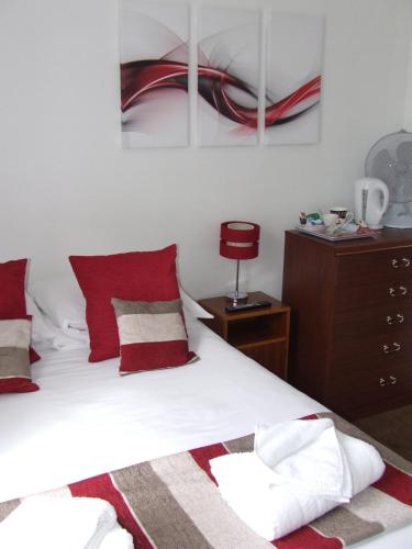 a bedroom with a bed with red and white pillows at Alexandra Guest House in Hemel Hempstead