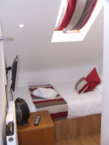a small bedroom with a bed and a window at Alexandra Guest House in Hemel Hempstead