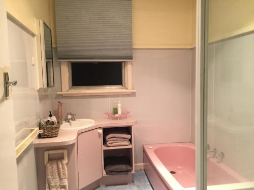 a bathroom with a pink tub and a sink and a shower at Growse House Yarram 3BR in Yarram