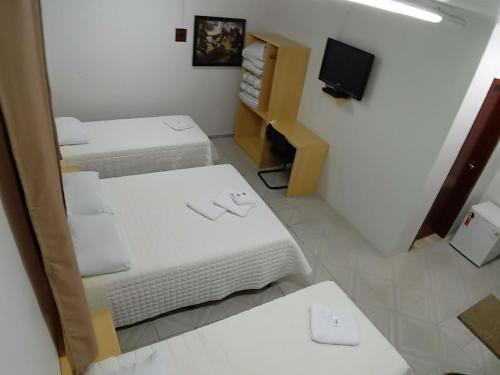 a small room with two beds and a tv at Giroto Hotel in Realeza