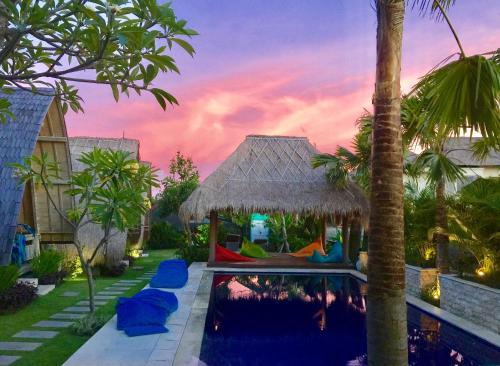 a villa with a swimming pool and a palm tree at The Hideaway Canggu in Canggu