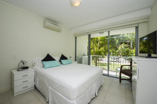 a bedroom with a white bed and a large window at Blue on Blue Apartment 813 in Nelly Bay