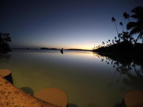 a person walking on the beach at sunset at Fiji Lodge Vosa Ni Ua in Savusavu