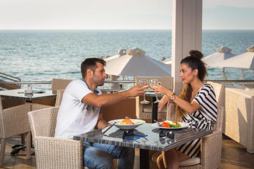a man and woman sitting at a table with a glass of wine at Acharavi Beach Hotel in Acharavi