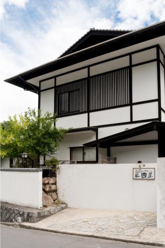 a white house with a black and white facade at Miyajima Guest House Mikuniya in Miyajima