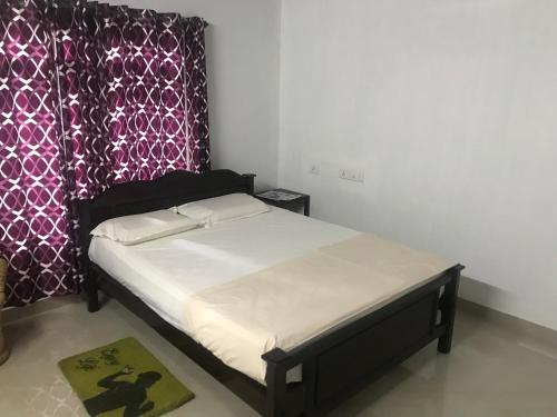 a bed in a bedroom with a purple curtain at Munroe Heritage Inn in Munroe Island