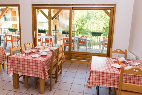 a dining room with two tables and a balcony at Vacancéole - Résidence Le Birdie in Giez