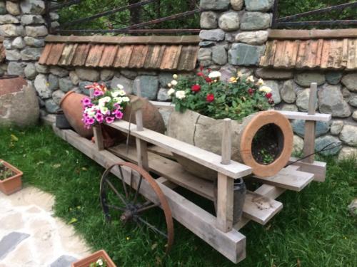 a wooden cart with flowers in it next to a stone wall at Hotel Restaurant Kakhaberi in Bibiliani