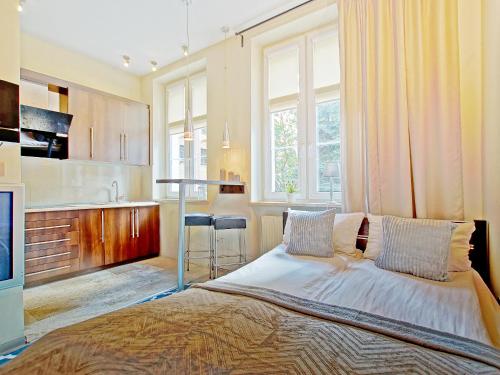 a bedroom with a large bed and a kitchen at Apartament Kameralny V in Gdańsk