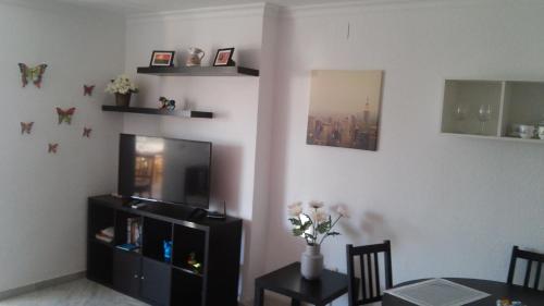 a living room with a television and a table and chairs at Apartamento El Coloso 4Q in Benalmádena