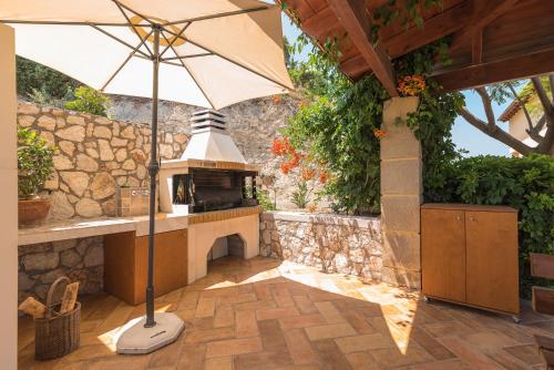 a patio with an umbrella and an outdoor oven at Villa Russelia in Kalavárda