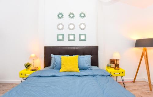 a bedroom with a blue bed and two yellow tables at Parliament & River View Apartments in Bucharest