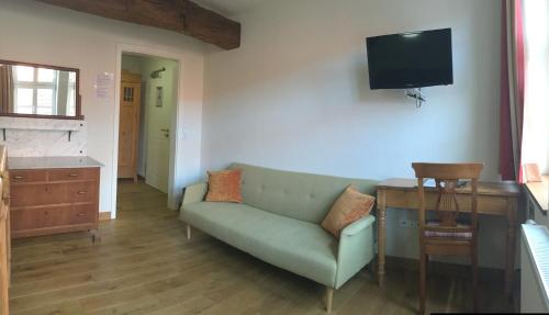 a living room with a couch and a television on the wall at Fachwerk-Hotel Eisenbart in Hannoversch Münden