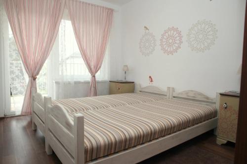 a bedroom with a large bed with pink curtains at Rozmaring Pihenőház in Velence