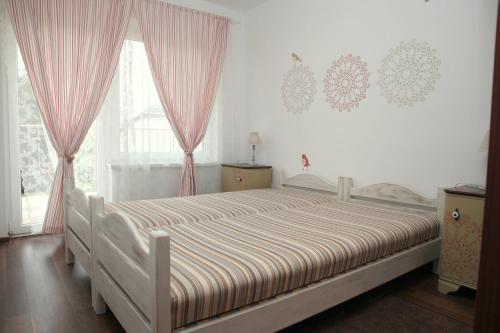 ヴァレンツァにあるRozmaring Pihenőházのベッドルーム1室(ピンクのカーテンが付いた大型ベッド1台付)