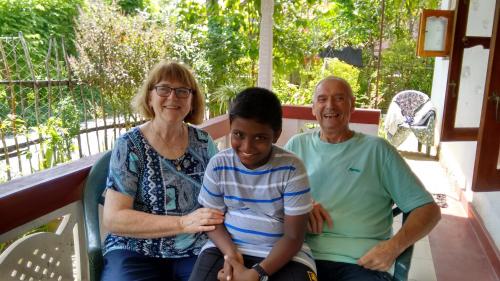 Eine Frau, ein Mann und ein Junge sitzen auf einer Veranda in der Unterkunft Gem Villa in Weligama