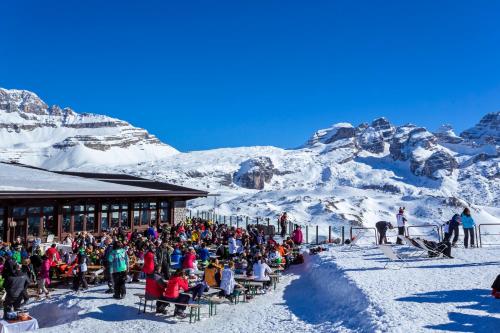 a crowd of people sitting at a ski lodge in the mountains at Hotel Chalet Del Sogno in Madonna di Campiglio