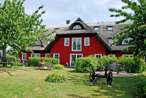 ein rotes Haus mit einer Bank im Hof in der Unterkunft Karolas Landhus unterm Reetdach in Neu Reddevitz