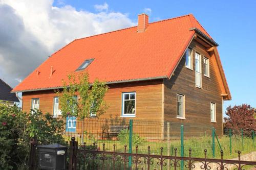 a house with an orange roof with a fence at Ferienwohnung in Gustow in Gustow