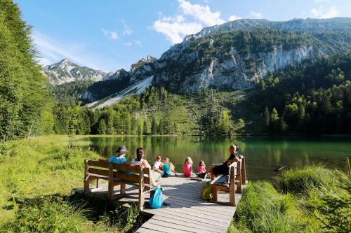 a group of people sitting on a wooden dock near a lake at Ferienwohnungen mit Bergblick in Inzell