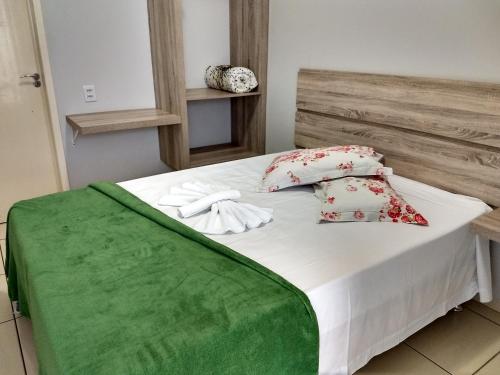 a bed with a green blanket and pillows on it at Vitória Hotel - Guaíra PR in Guaíra