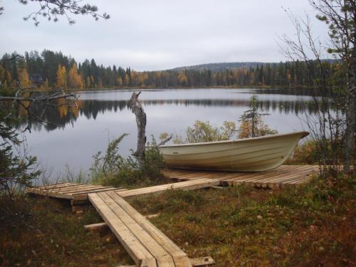 a boat sitting on a dock next to a lake at Hakamajat Cottages in Syöte