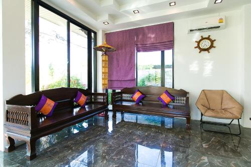 a living room with two couches and a clock at SakSukSmile Resort in Sukhothai