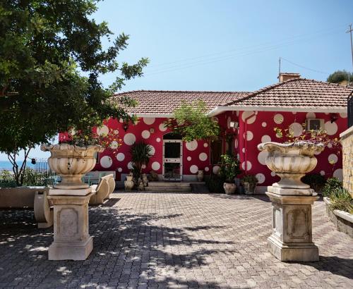 a red building with two large vases in front of it at B&B Vento di Scirocco in Favara