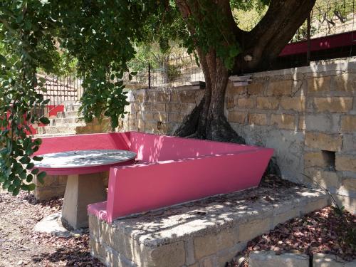 a pink bench sitting in front of a tree at B&B Vento di Scirocco in Favara