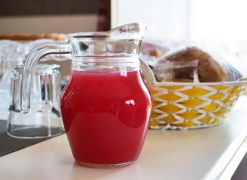 a glass jar filled with red liquid next to a basket of bread at B&B Vento di Scirocco in Favara