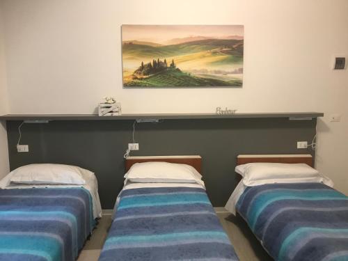 two beds in a room with a painting on the wall at Albergo Chiara in Savignone