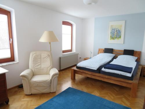 een slaapkamer met een bed en een stoel bij FEWO am Dümmer-See in Lembruch