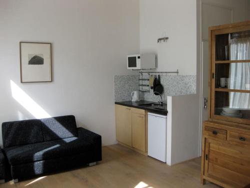 uma sala de estar com uma cadeira preta e uma cozinha em Studio-apartment in city-center em Amsterdã