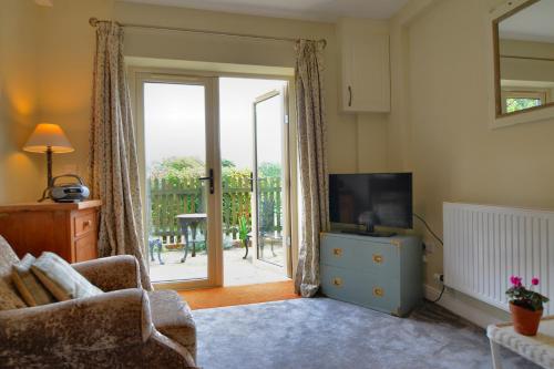 a living room with a television and a sliding glass door at Pine Tree Lodge, Bridgnorth in Bridgnorth