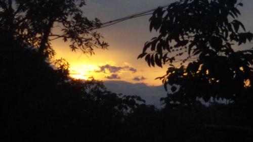 a sunset in the sky with trees in the foreground at GreenSpot Homestay in Idukki
