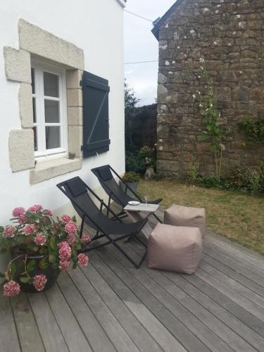 a black chair sitting on a wooden deck with flowers at Les chambres du Keriolet in La Trinité-sur-Mer