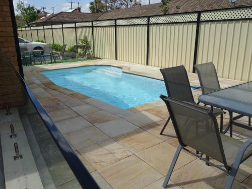 a swimming pool in a backyard with a table and chairs at Centrepoint Motel in Dubbo