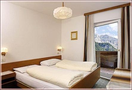 a bedroom with a bed and a large window at Garni Sayonara in Selva di Val Gardena
