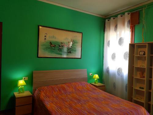 ein grünes Schlafzimmer mit einem Bett und einer grünen Wand in der Unterkunft B&B William in Padua